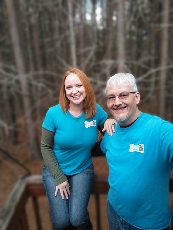 Mike and Christina Walker pose standing on their back deck wearing jeans and blue Top Dog shirts